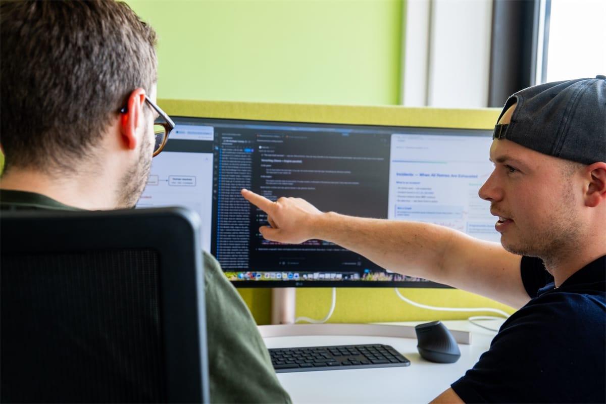 Zwei Entwickler im Miragon-Büro, einer zeigt auf eine Stelle im Code